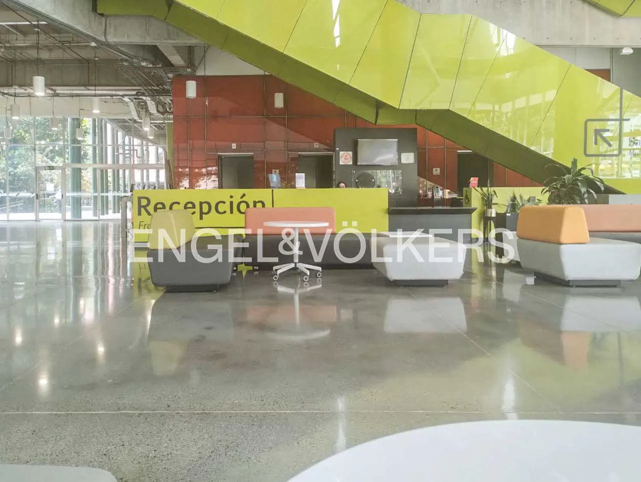 Engel & Völkers office lobby with reception desk, modern seating, and a bright yellow staircase.