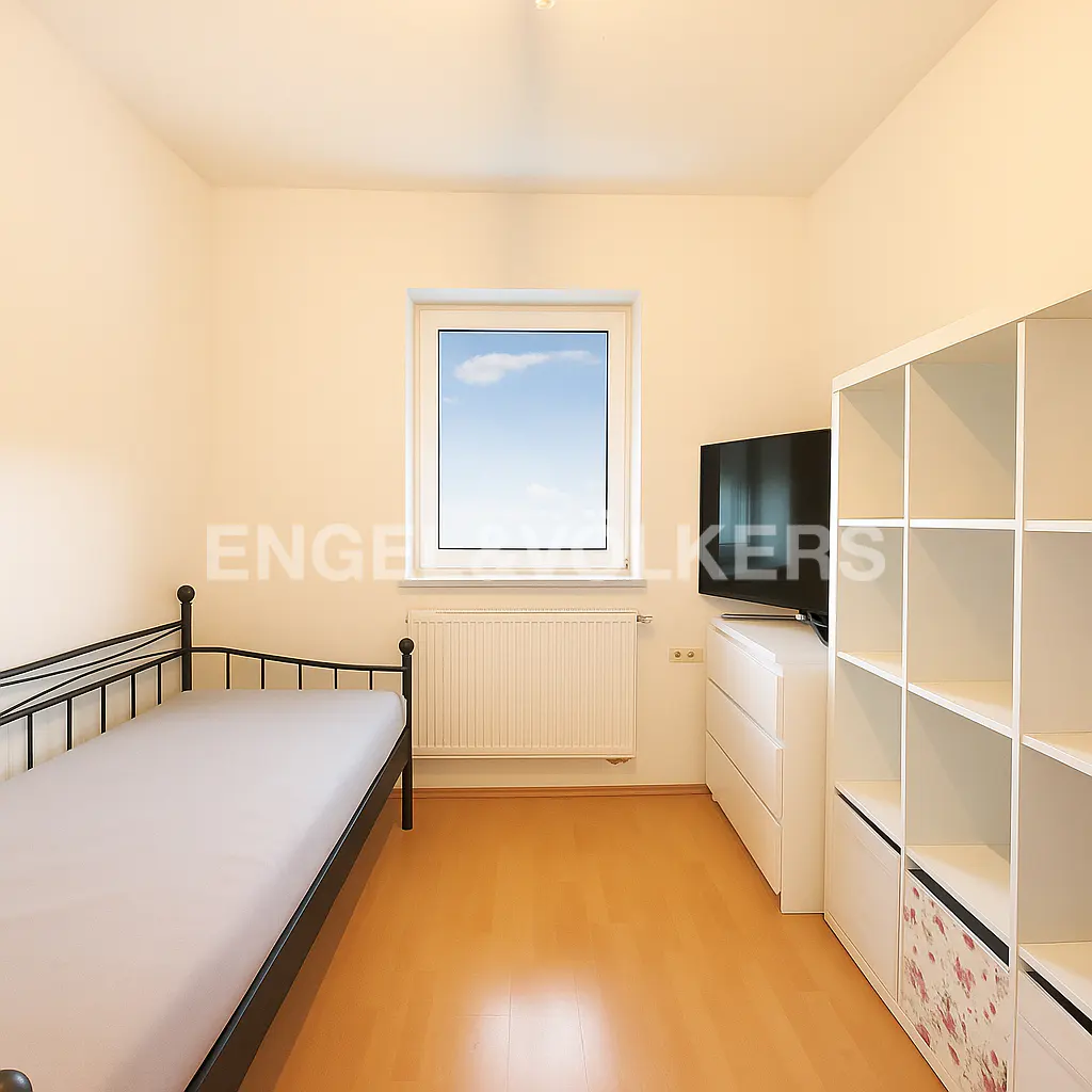 Bedroom with a black metal bed frame, white walls, wood floor, window, TV, dresser, and white shelving unit.