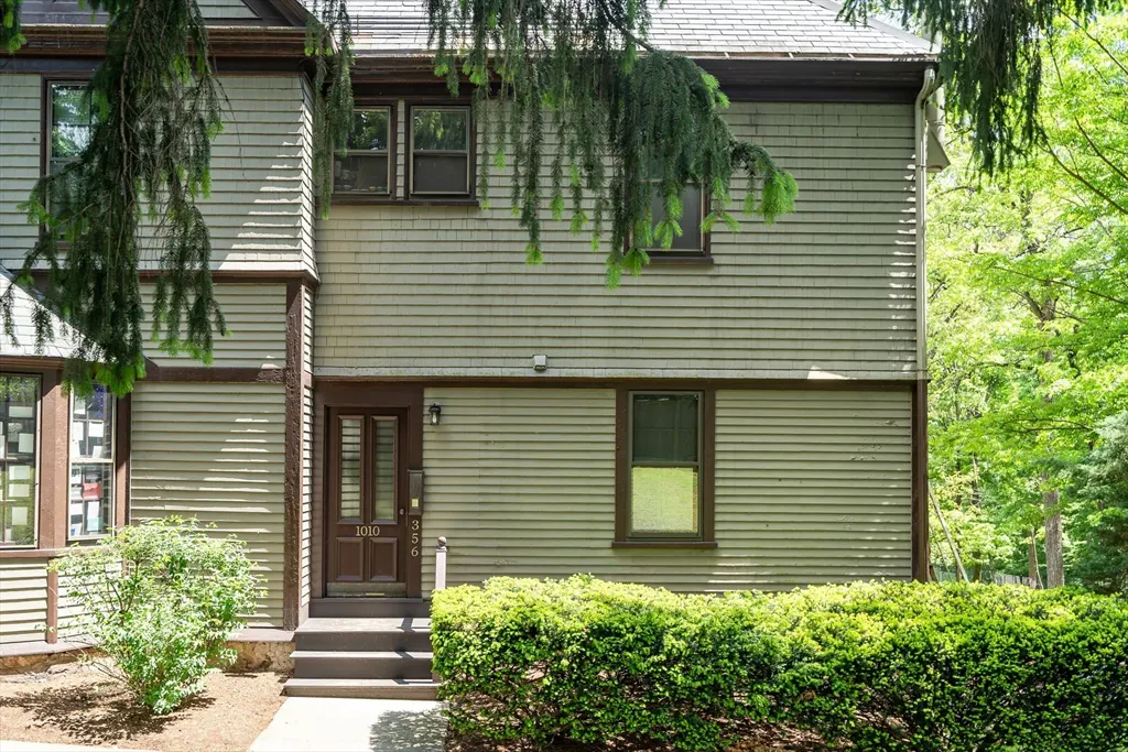 A two-story house with light green siding, brown trim, and a dark brown front door with the number 1010 on it.