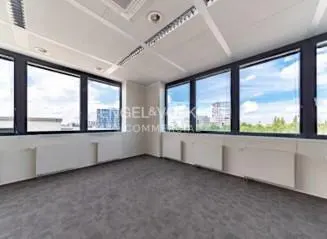 Empty office space with gray carpet, white walls, and large windows with city views.