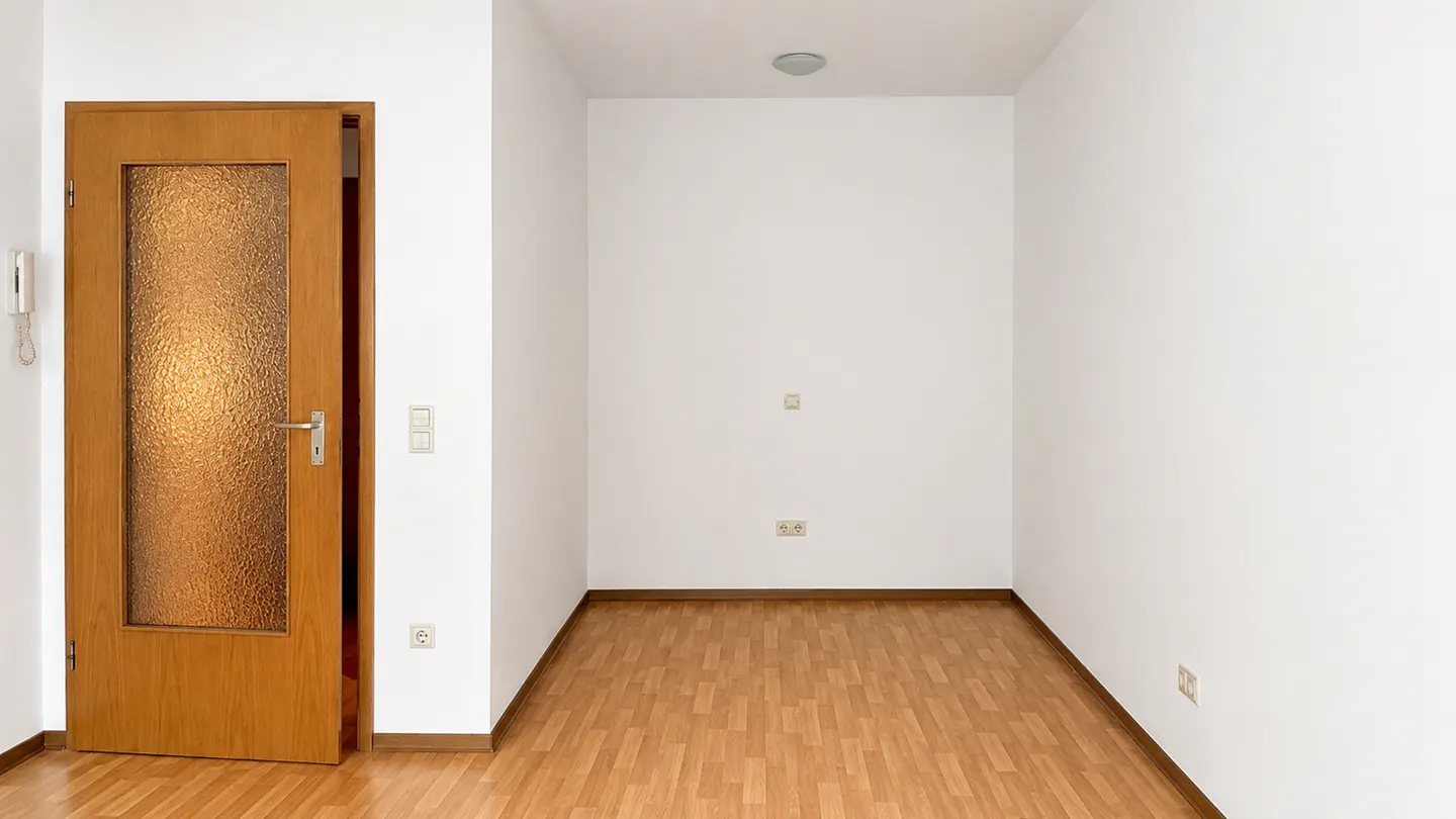 An interior shot of a room with wood floors, white walls, and a partially open wood door with textured glass.