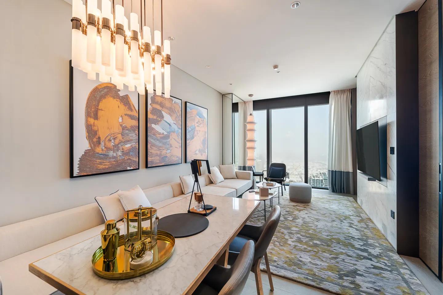 A modern living room with a white sofa, marble table, and abstract art. A large window offers a city view.