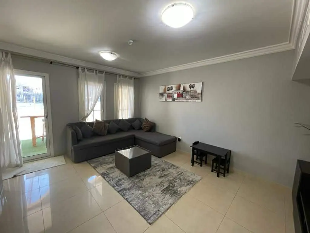 Living room with gray sectional sofa, square coffee table on a gray rug, and a small black table with two chairs.