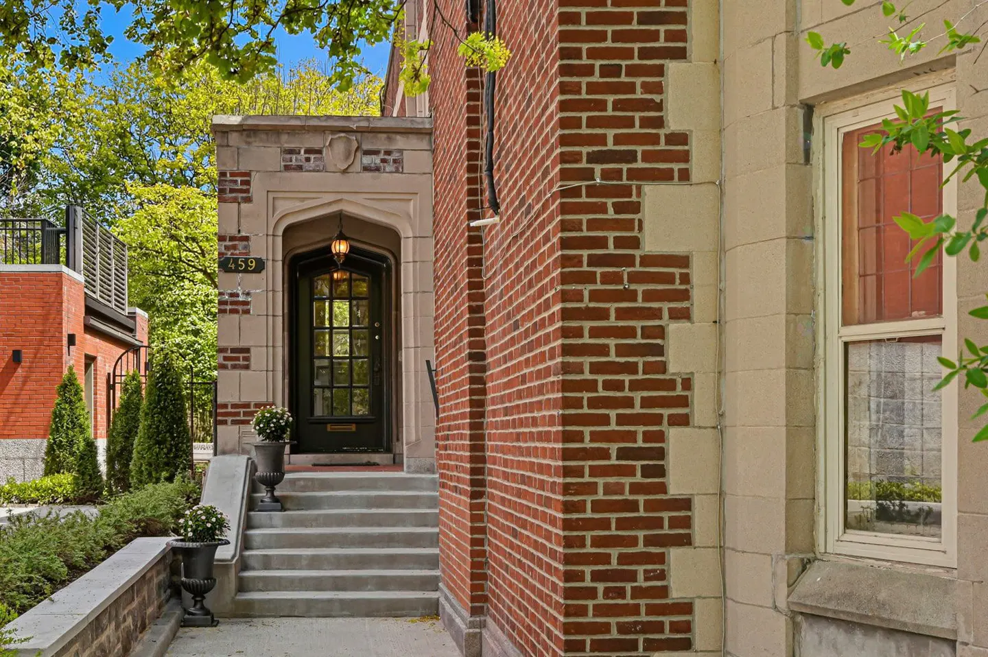 Exterior view of a brick house with stone trim, steps leading to a dark wood door with glass panes, and the house number 459 above the door.