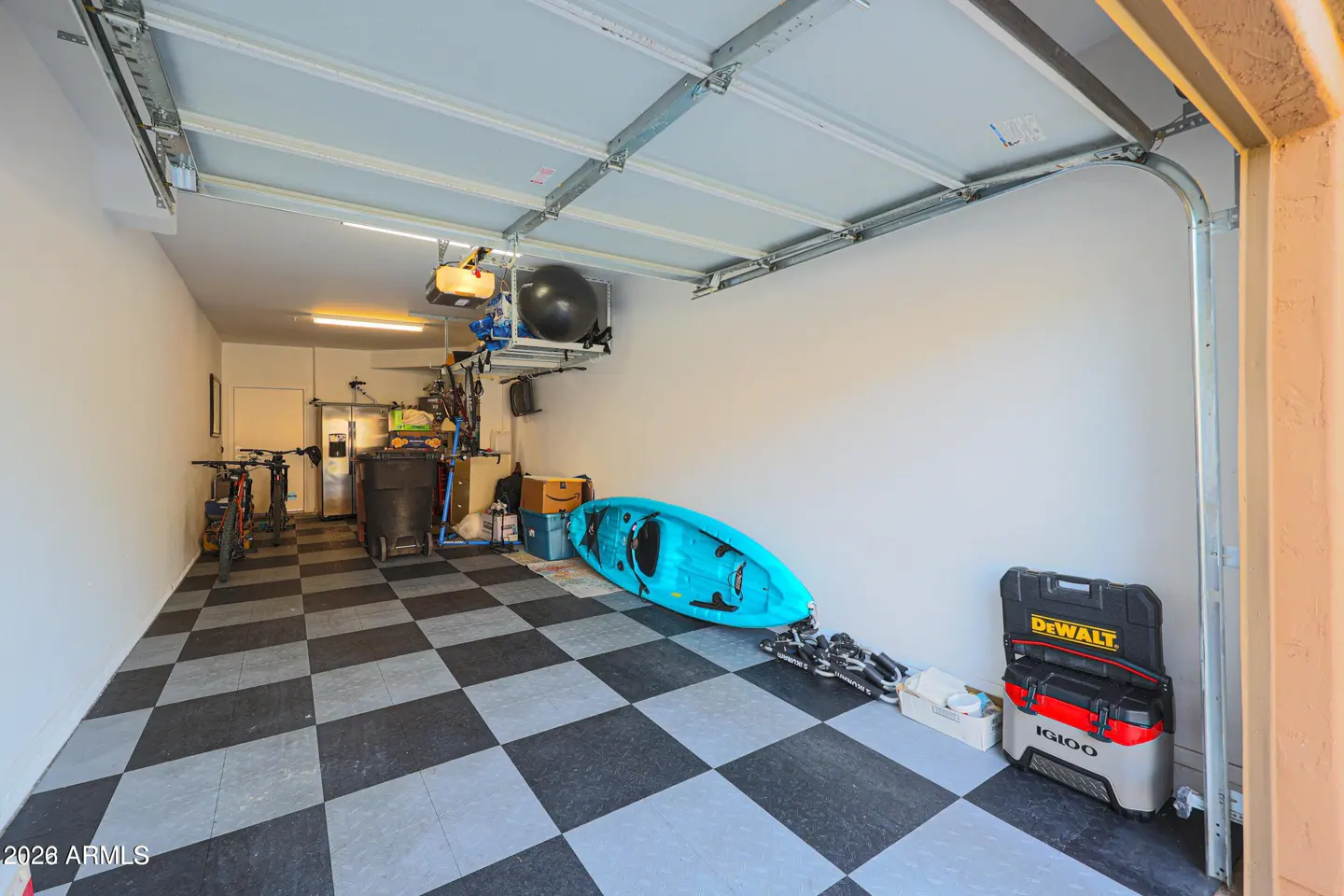 A well-organized garage with a black and gray checkered floor, storage racks, and a blue kayak.
