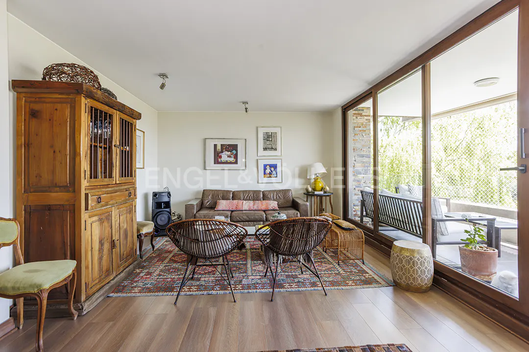 Living room with wood floors, brown leather sofa, two wicker chairs, and sliding glass doors to a balcony.