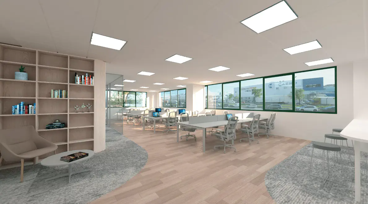 Bright office space with desks, chairs, and computers. Large windows offer natural light. A bookshelf and seating area add a cozy touch.
