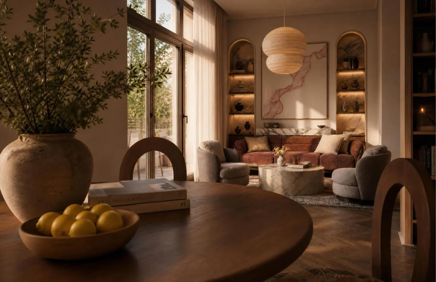 Warm, modern living room with a round wooden table, bowl of lemons, plush sofa, armchairs, and arched built-in shelving.