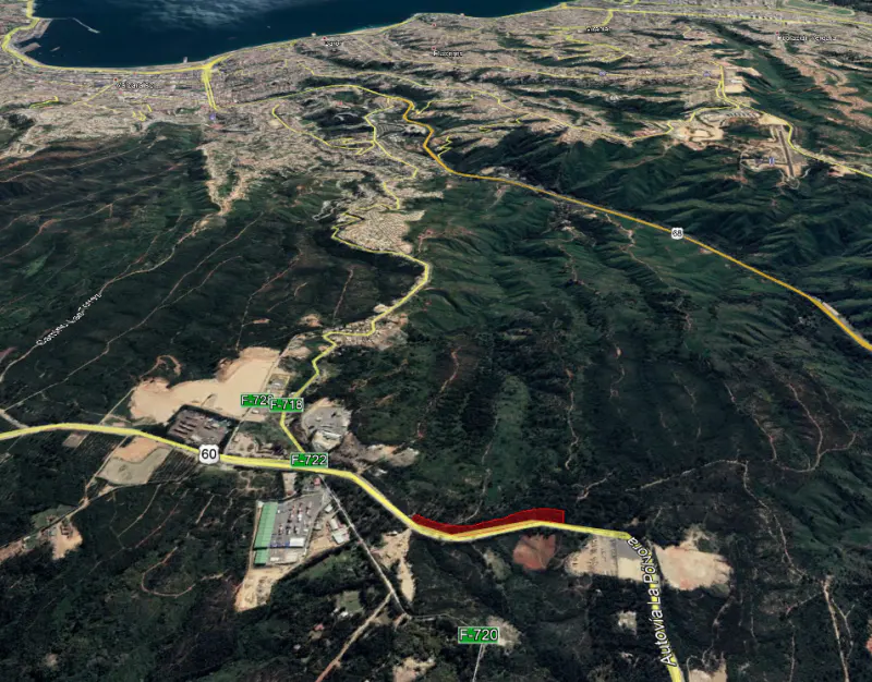 Aerial view of a winding yellow highway through green hills, with a red section highlighted.