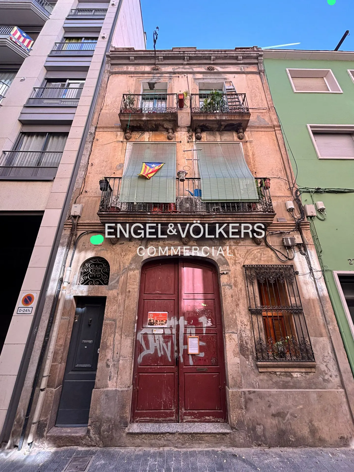 Exterior of Engel & Völkers Commercial building with red doors, balconies, and a Catalan flag.