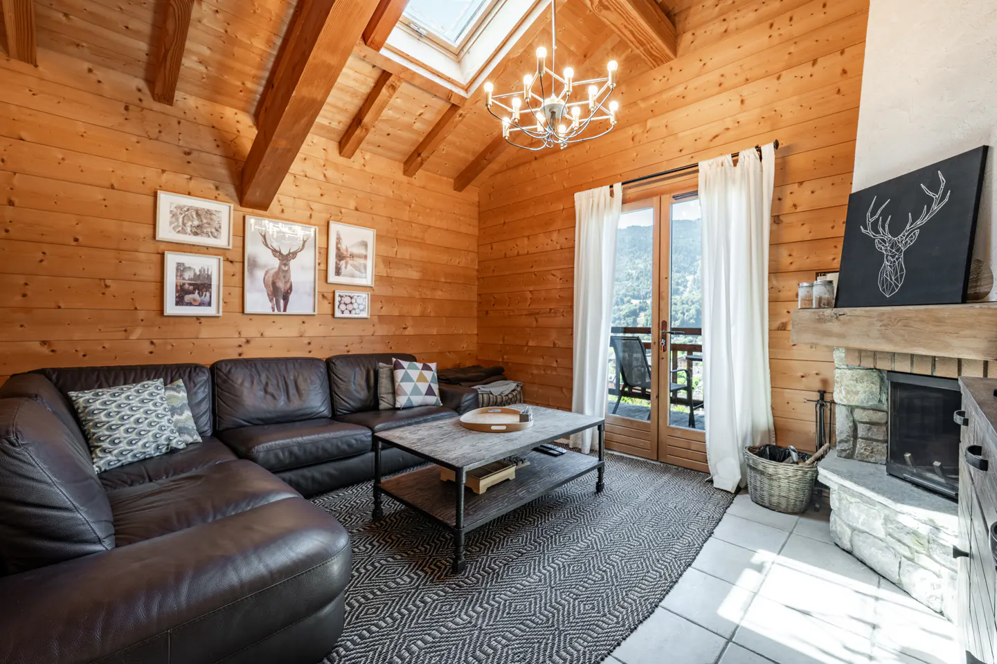 Living room with wood walls, a leather sectional, a stone fireplace, and a balcony with a mountain view.