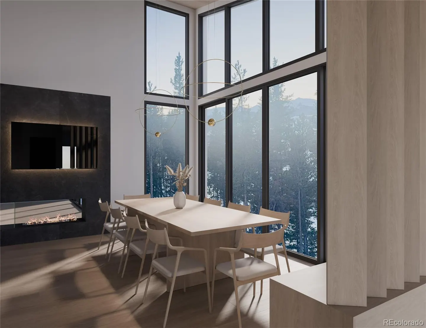 A modern dining room with a long light wood table, chairs, and a view of a snowy forest through large windows. A fireplace is on the left.