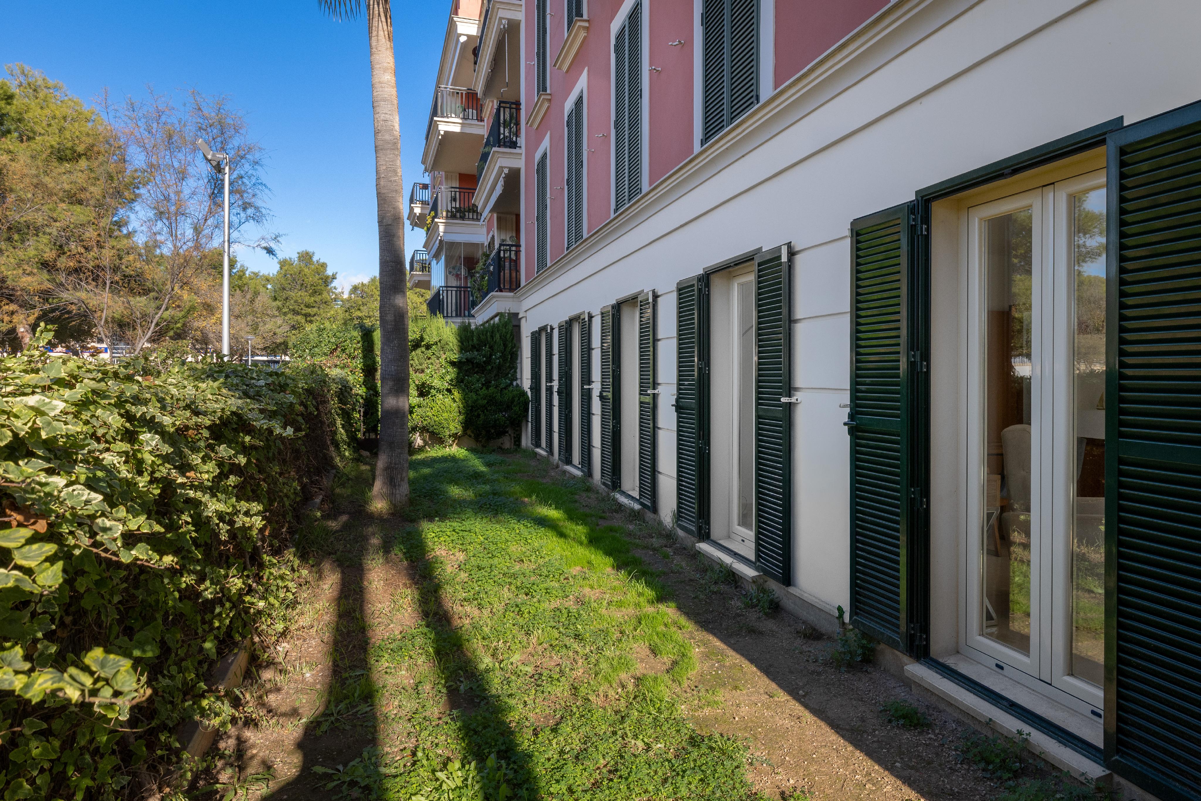 Exterior view of a pink building with green shutters and a grassy yard.