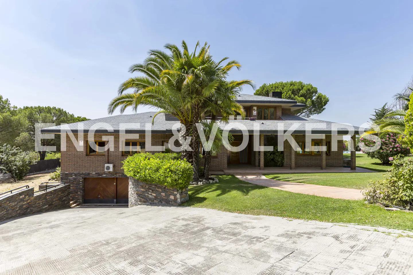 Exterior of a two-story brick house with a gray roof, palm tree, and green lawn on a sunny day.