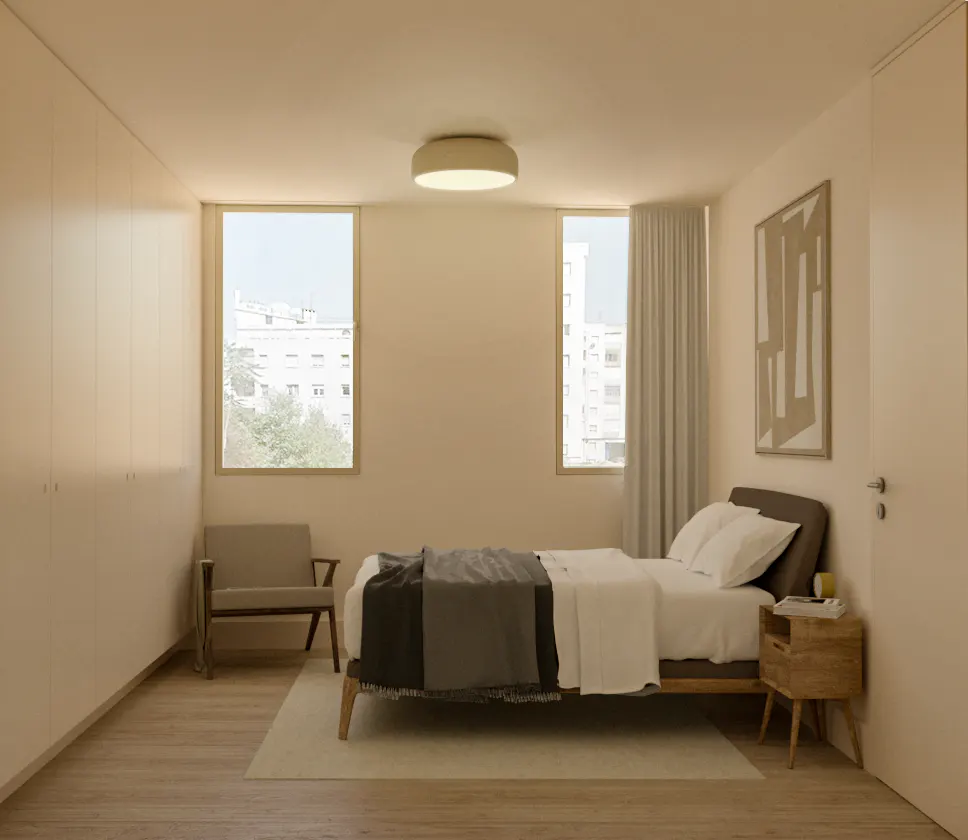 A bright bedroom with a bed, chair, and nightstand. Two windows offer a city view. A modern art piece hangs on the wall.