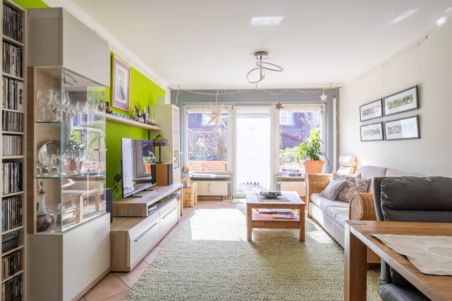 Bright living room with a green accent wall, light wood furniture, a sofa, and a large window.