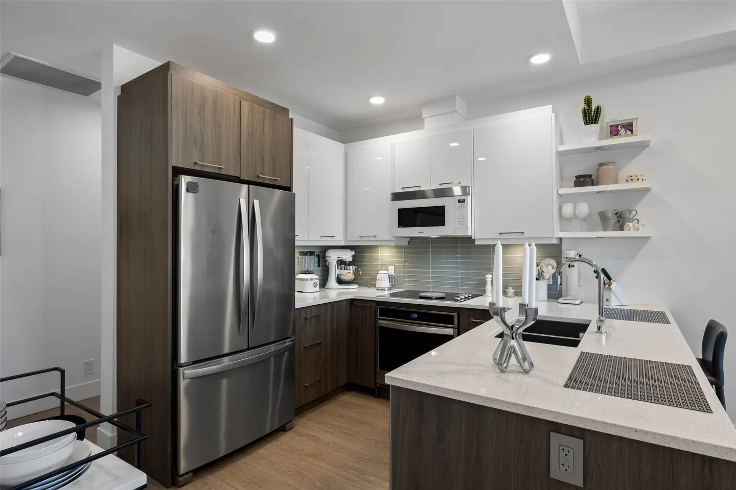 A modern kitchen with stainless steel appliances, white cabinets, and a white countertop island.