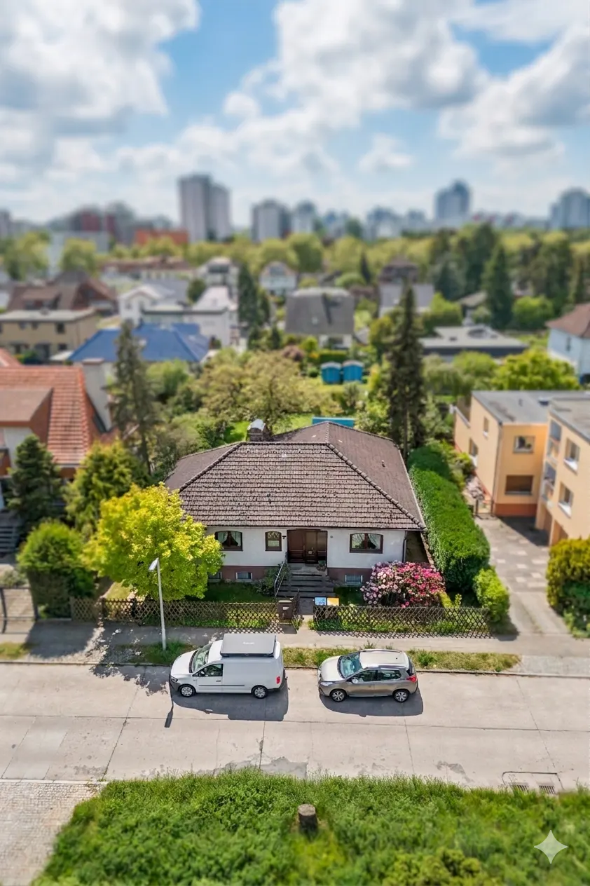 Aerial view of a one-story house with a brown roof, green lawn, and two cars parked on the street.