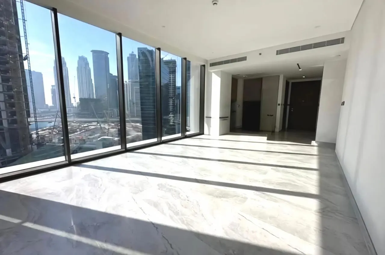 Empty room with marble floors and floor-to-ceiling windows overlooking a city skyline.