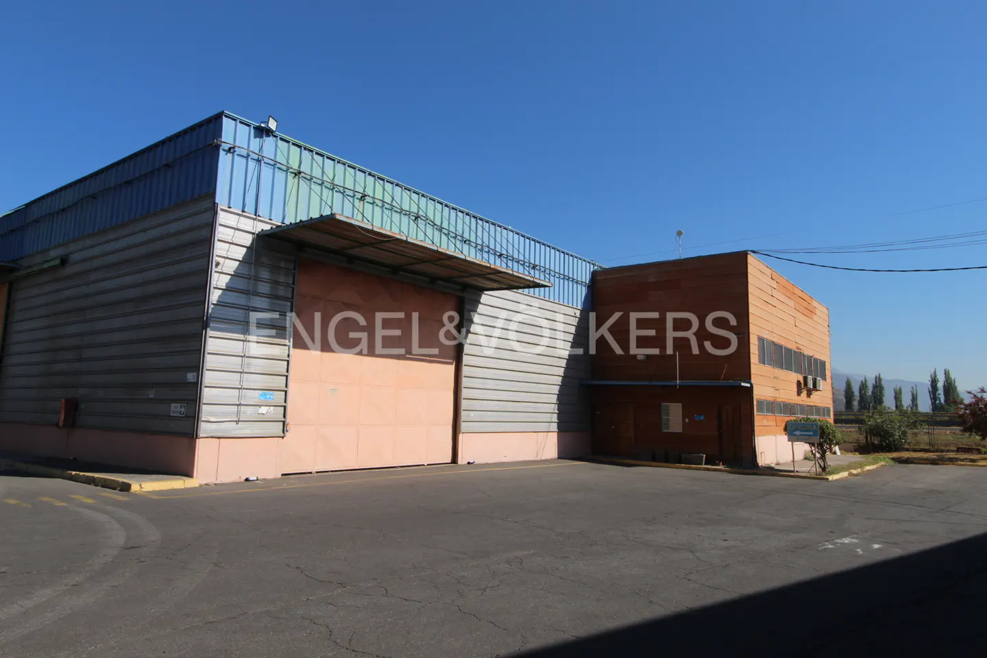Exterior view of a large, industrial Engel & Volkers building with a loading dock and a blue sky.
