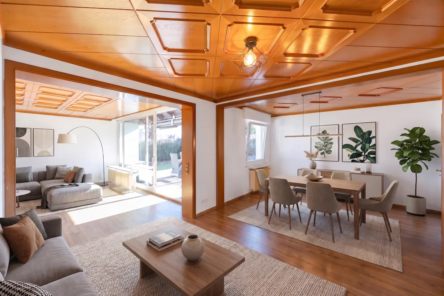 A bright, open-concept living and dining room with wood floors and a paneled wood ceiling. A gray sofa and dining set are visible.