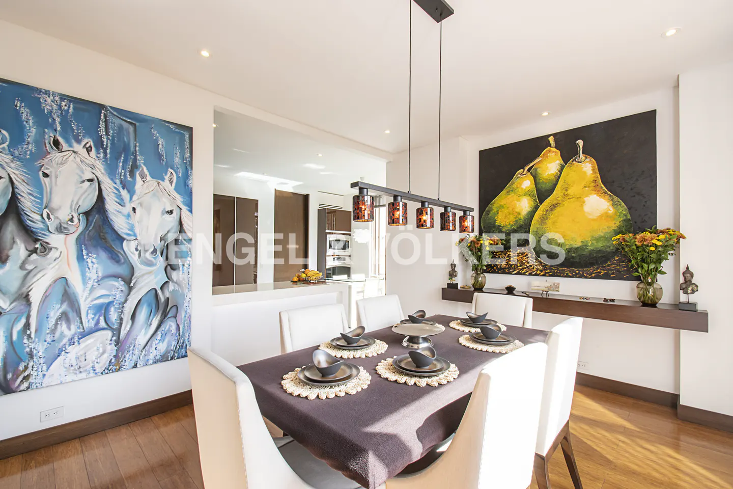 Dining room with wood floors, white chairs, and a table set for six. Artwork of horses and pears adorn the walls.