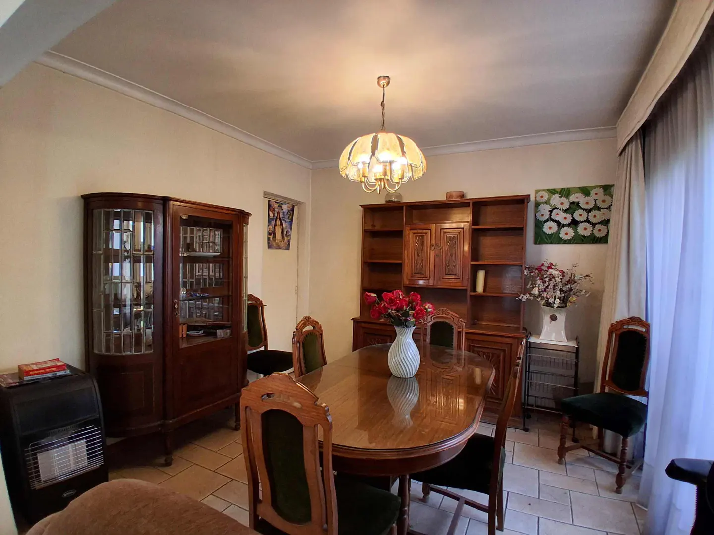 A dining room with a wooden table, chairs, and cabinets. A chandelier hangs above the table.