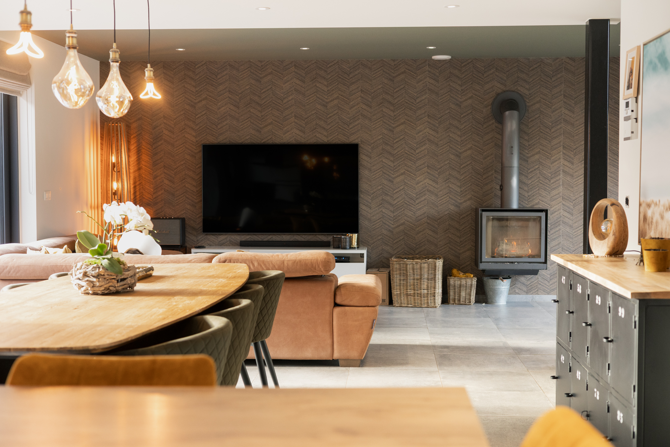 A modern living room with a wood dining table, a brown sofa, a TV, and a fireplace.