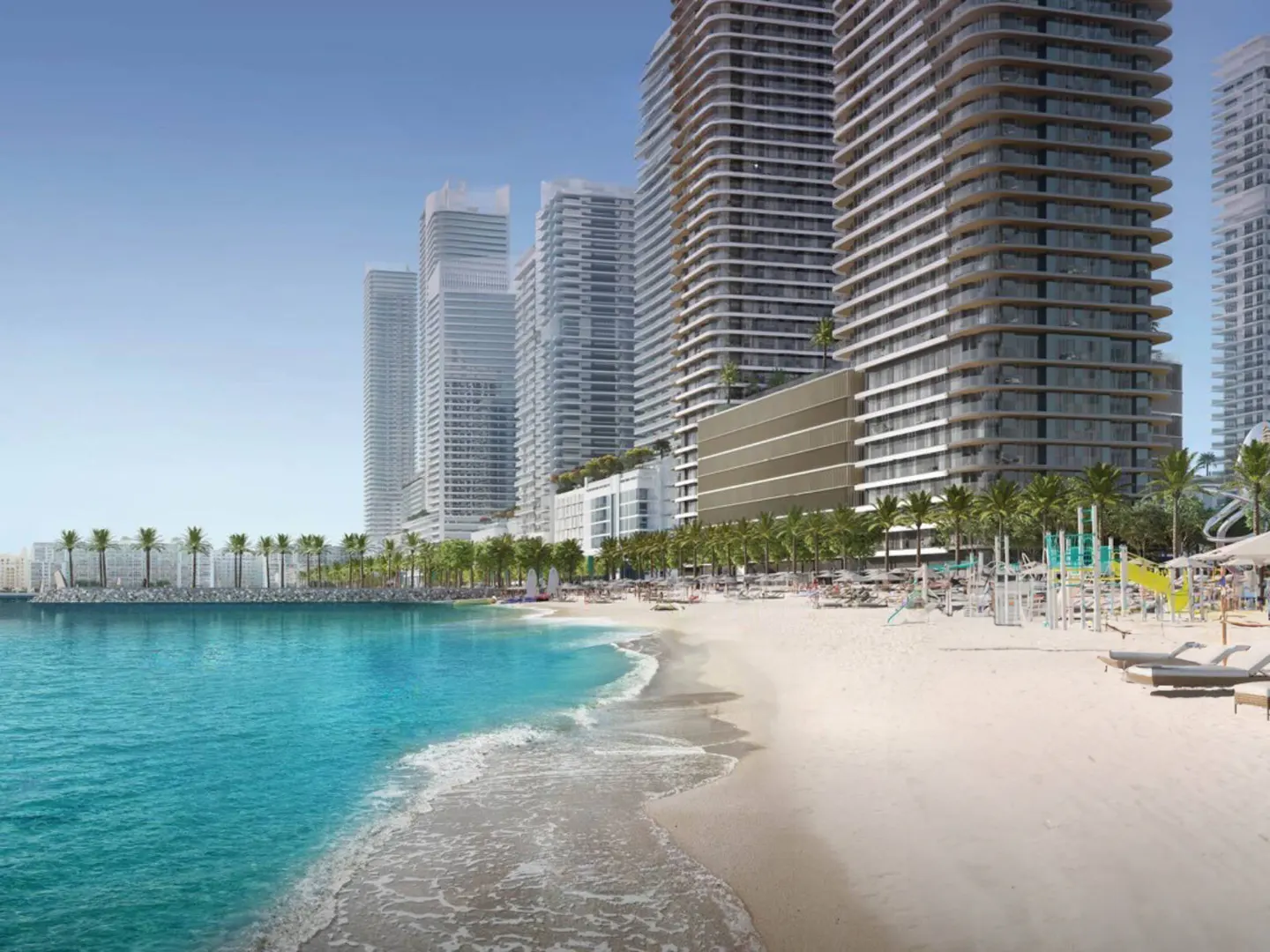 Beachfront property view with tall, modern apartment buildings, palm trees, and turquoise water. Sandy beach with lounge chairs.