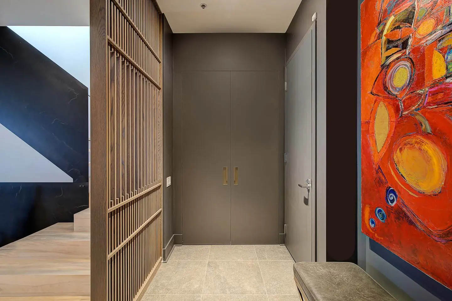 Hallway with a wooden screen, gray doors, and a colorful painting. Stairs are visible in the background.