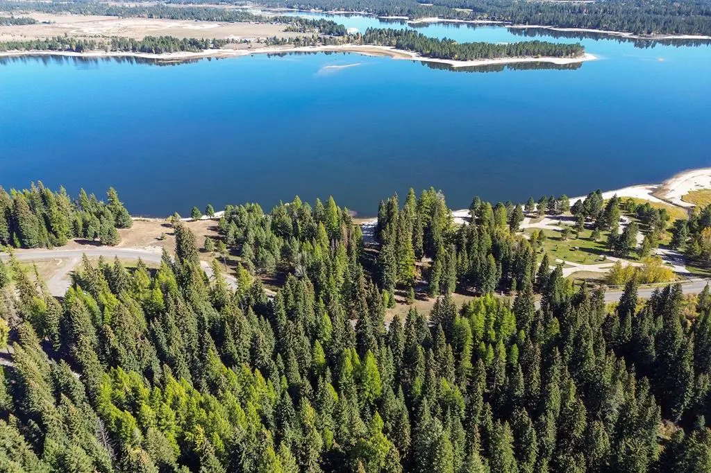 Aerial view of a blue lake surrounded by green trees and a sandy beach.