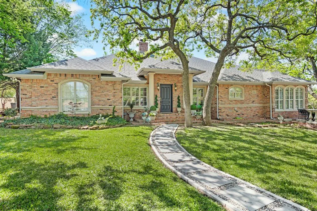 A single-story brick house with a gray roof, a stone walkway, and green grass.