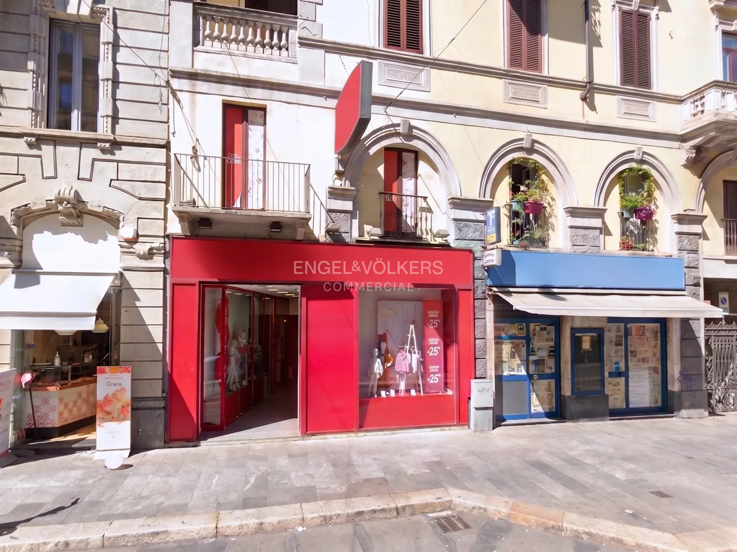Exterior view of Engel & Völkers Commercial real estate office with a red facade, located on a city street.