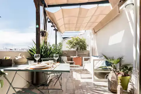 Outdoor patio with a table set for dining, plants, and a retractable awning overhead.
