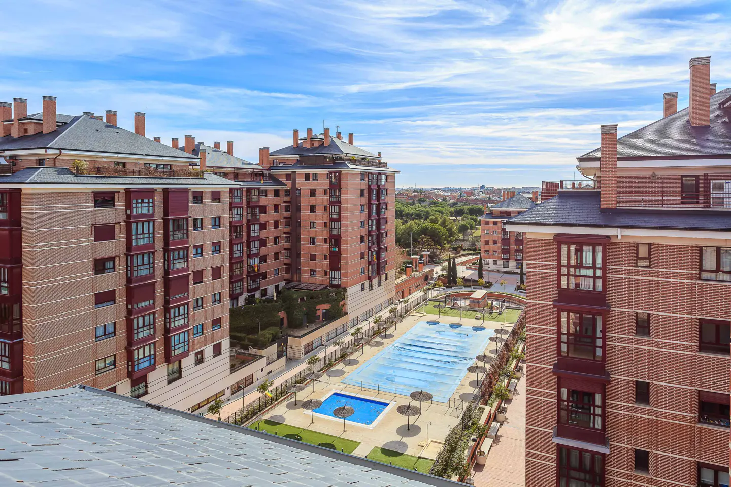 Aerial view of brick apartment buildings with a covered pool and blue sky.