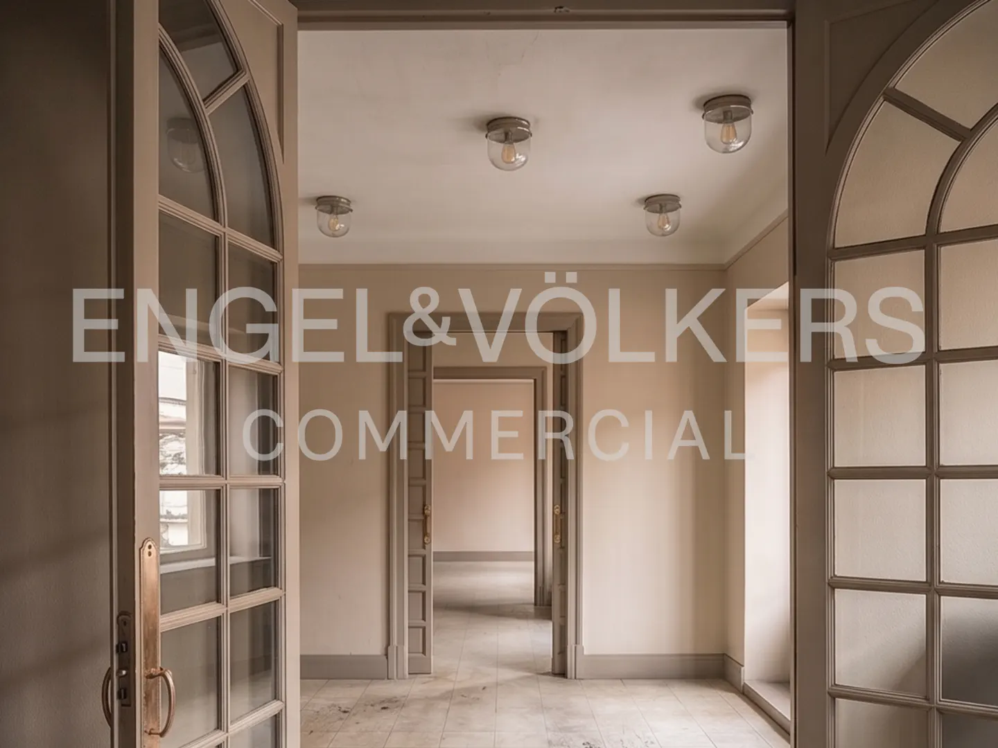 View through arched glass doors into a series of minimalist, beige-toned rooms with matching door frames and ceiling lights.