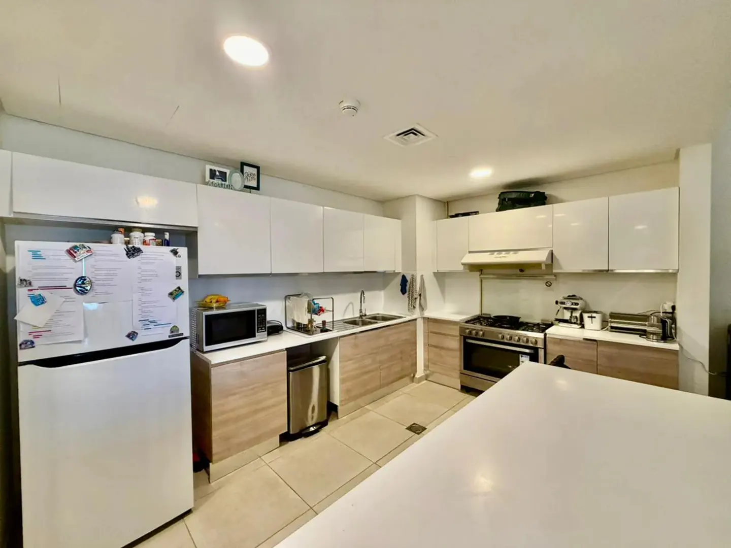A bright kitchen with white cabinets, stainless steel appliances, and a large white island.
