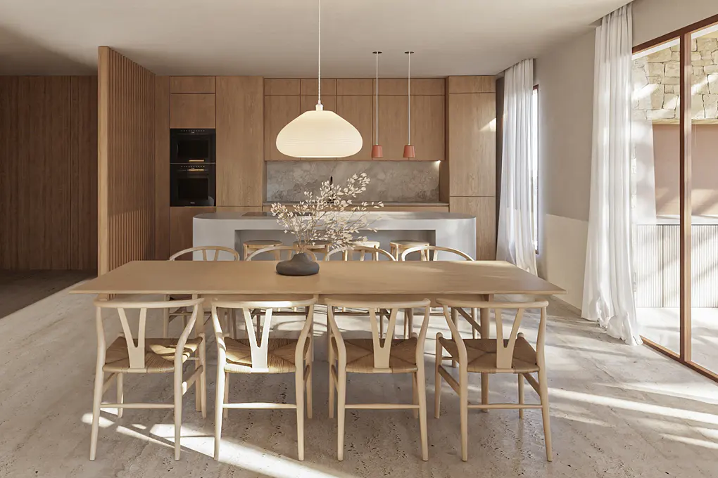 A bright, modern dining room with a light wood table and chairs. A vase of flowers sits in the center of the table. The kitchen is in the background.