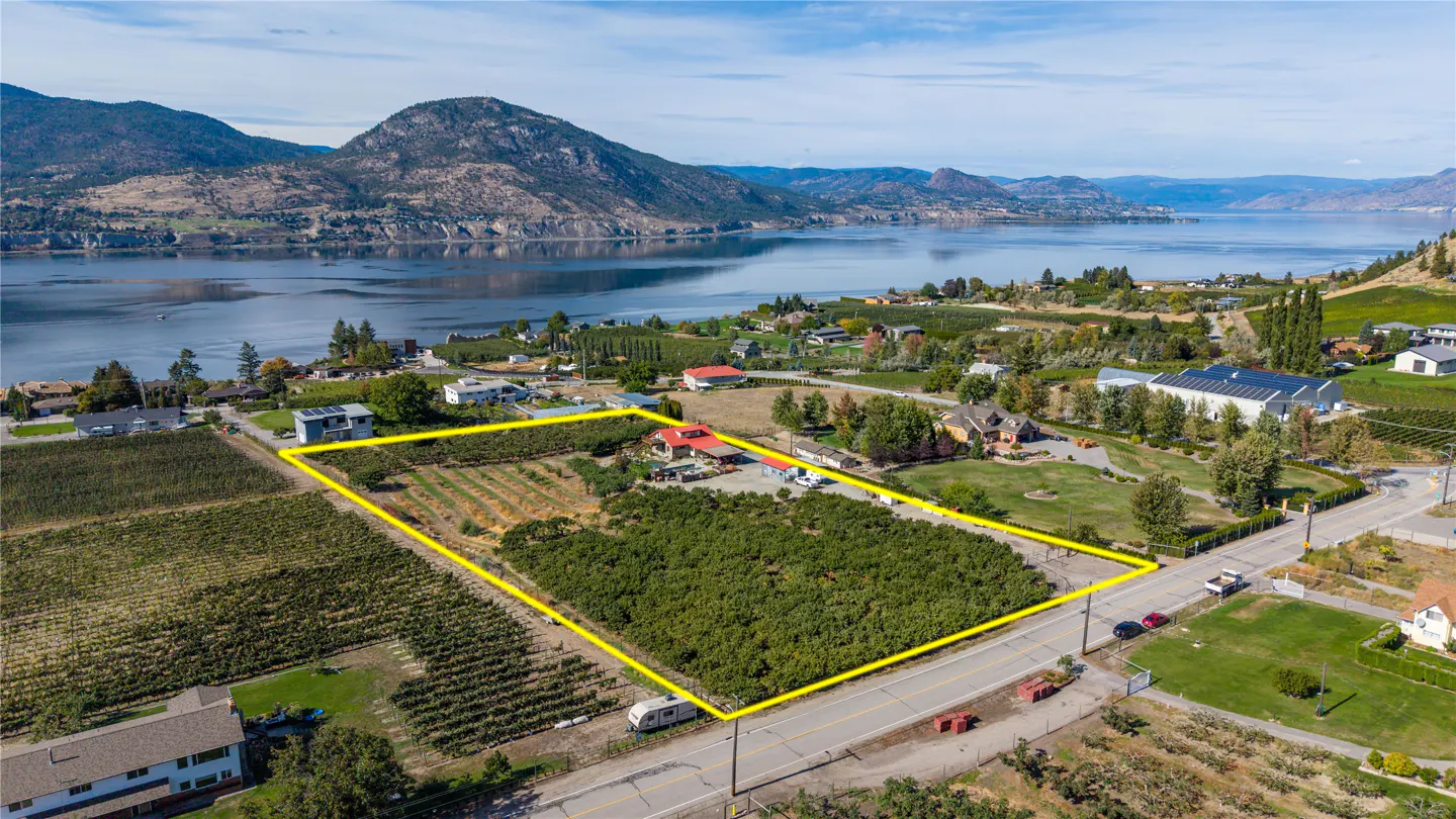 Aerial view of a vineyard property outlined in yellow, with a lake and mountains in the background.