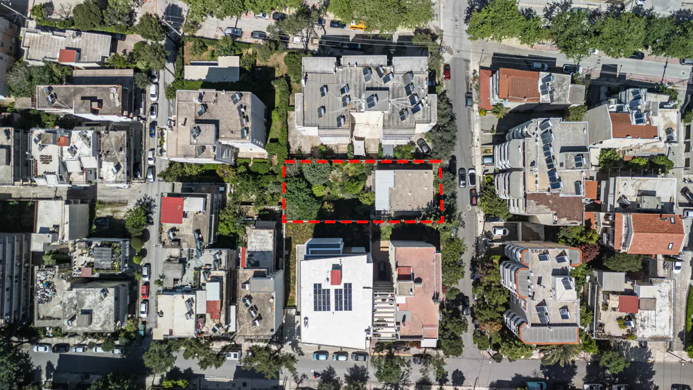Aerial view of a property outlined in red, surrounded by buildings and trees in a residential area.
