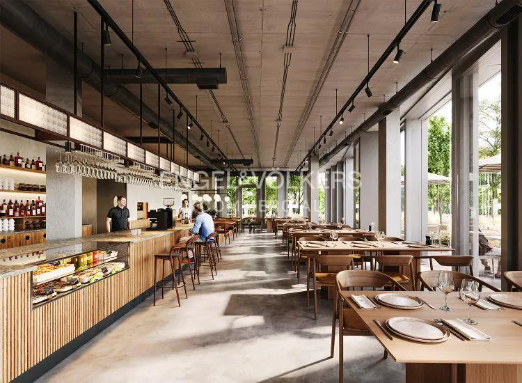 Interior view of a modern restaurant with wooden tables and chairs, a bar with a display case, and large windows overlooking greenery.