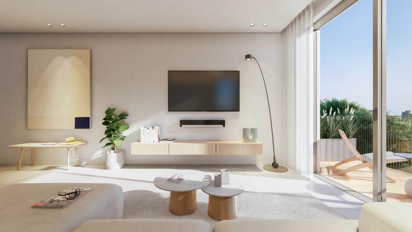 Bright living room with a TV, light wood furniture, and a large painting. A deck with a lounge chair is visible through sliding glass doors.