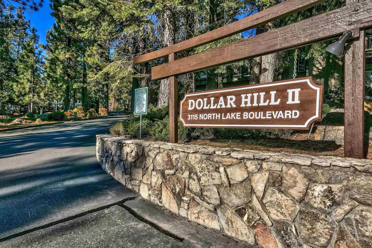 Dollar Hill II sign at 3115 North Lake Boulevard, with a stone wall base and trees in the background.