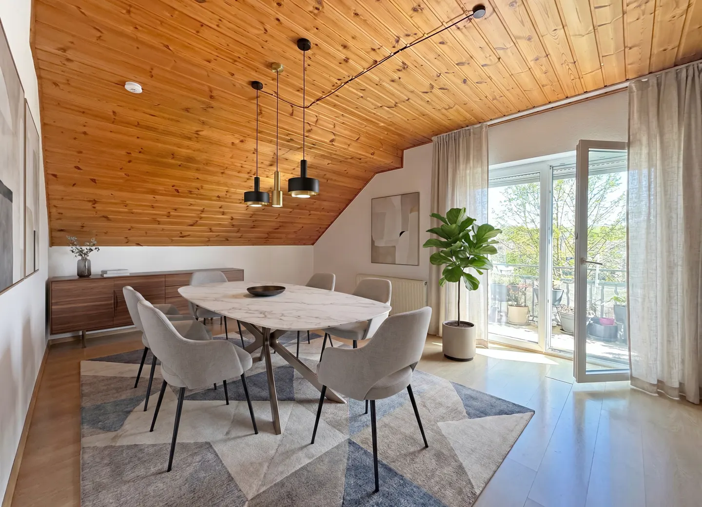 A dining room with a wood ceiling, a marble table with six chairs, and a balcony with an open door.