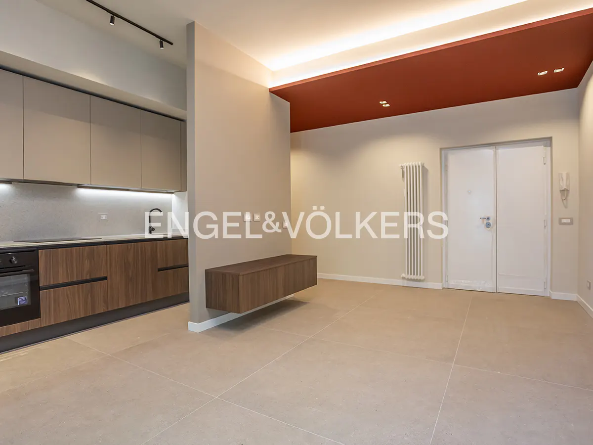 A modern apartment interior with a kitchen, floating cabinet, radiator, and white double doors.
