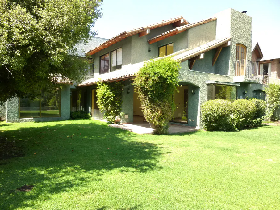 Two-story green house with a brown roof and a green lawn in front of it.