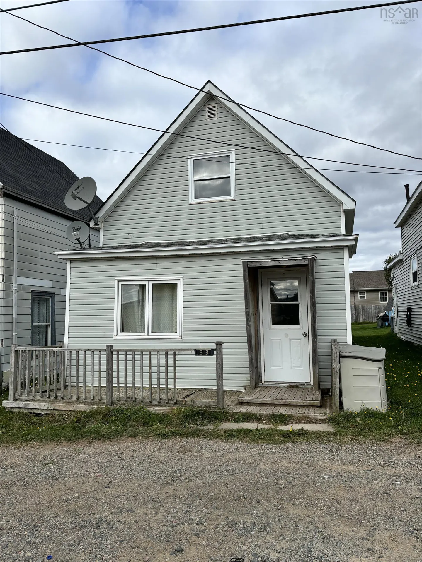 Exterior view of a two-story house with light gray siding, white trim, and a small porch with a wooden railing.