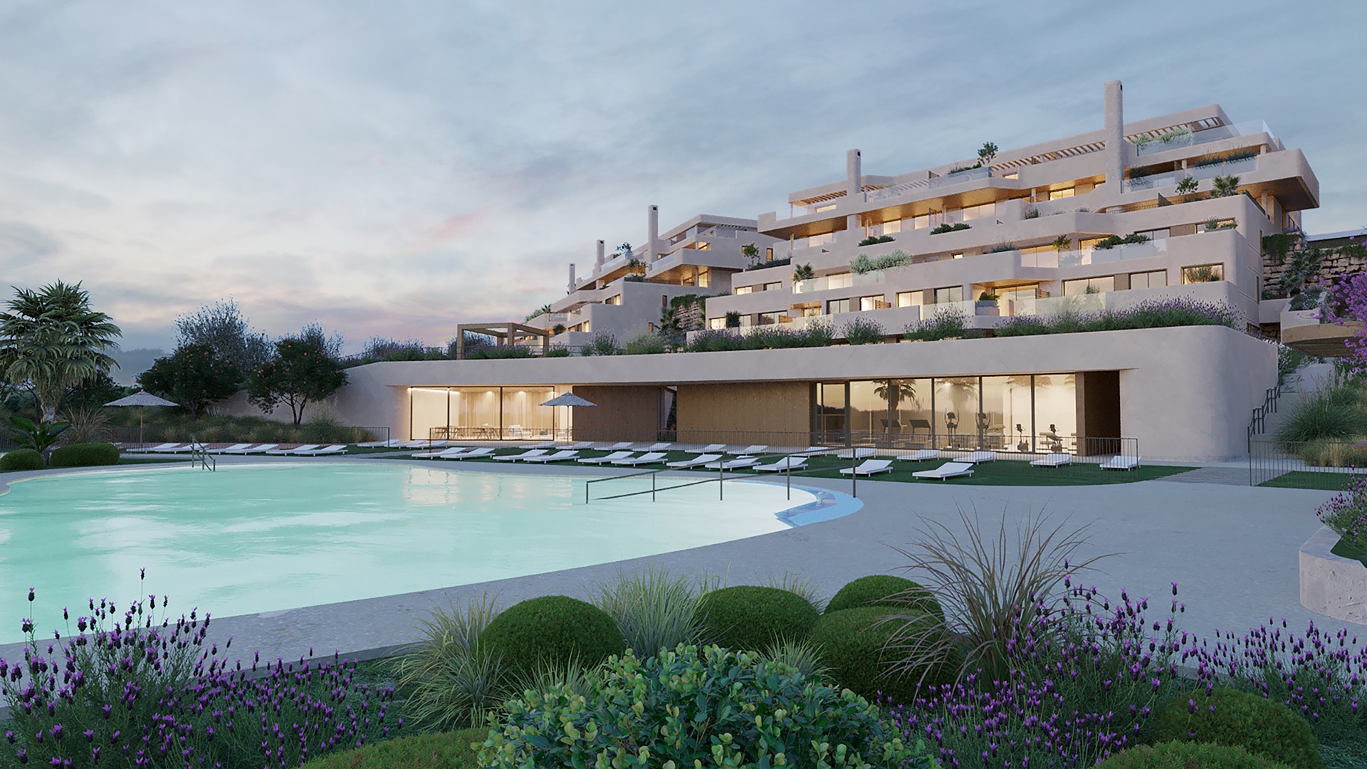 Exterior view of a modern, multi-story beige apartment building with a large pool, lounge chairs, and manicured landscaping.