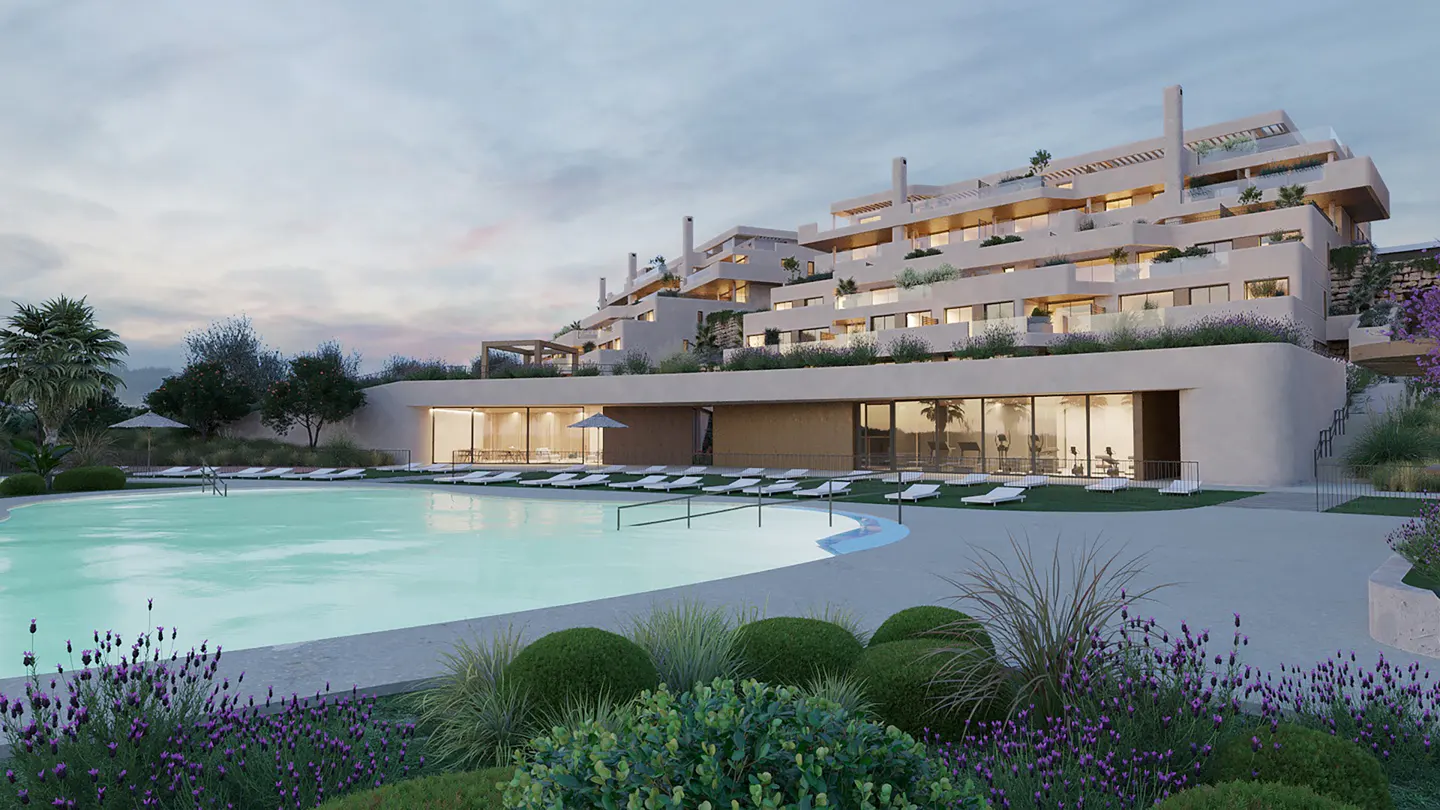 Exterior view of a modern, multi-story beige apartment building with a large pool, lounge chairs, and manicured landscaping.