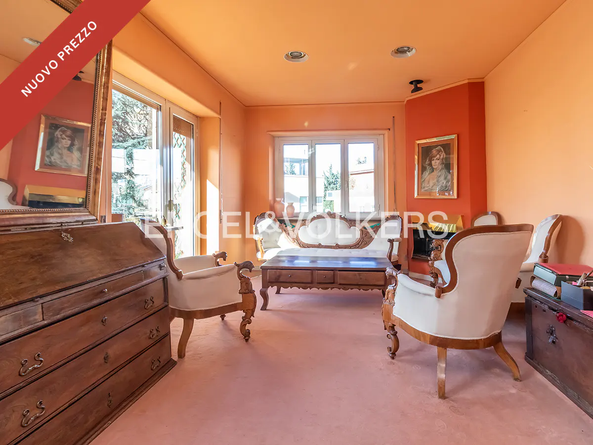 Living room with peach walls, vintage wooden furniture, white upholstered chairs, a coffee table, and a large mirror.